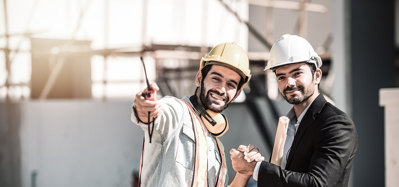 Abbildung: Impressum - zwei junge Handwerker mit Schutzhelmen auf der Baustelle